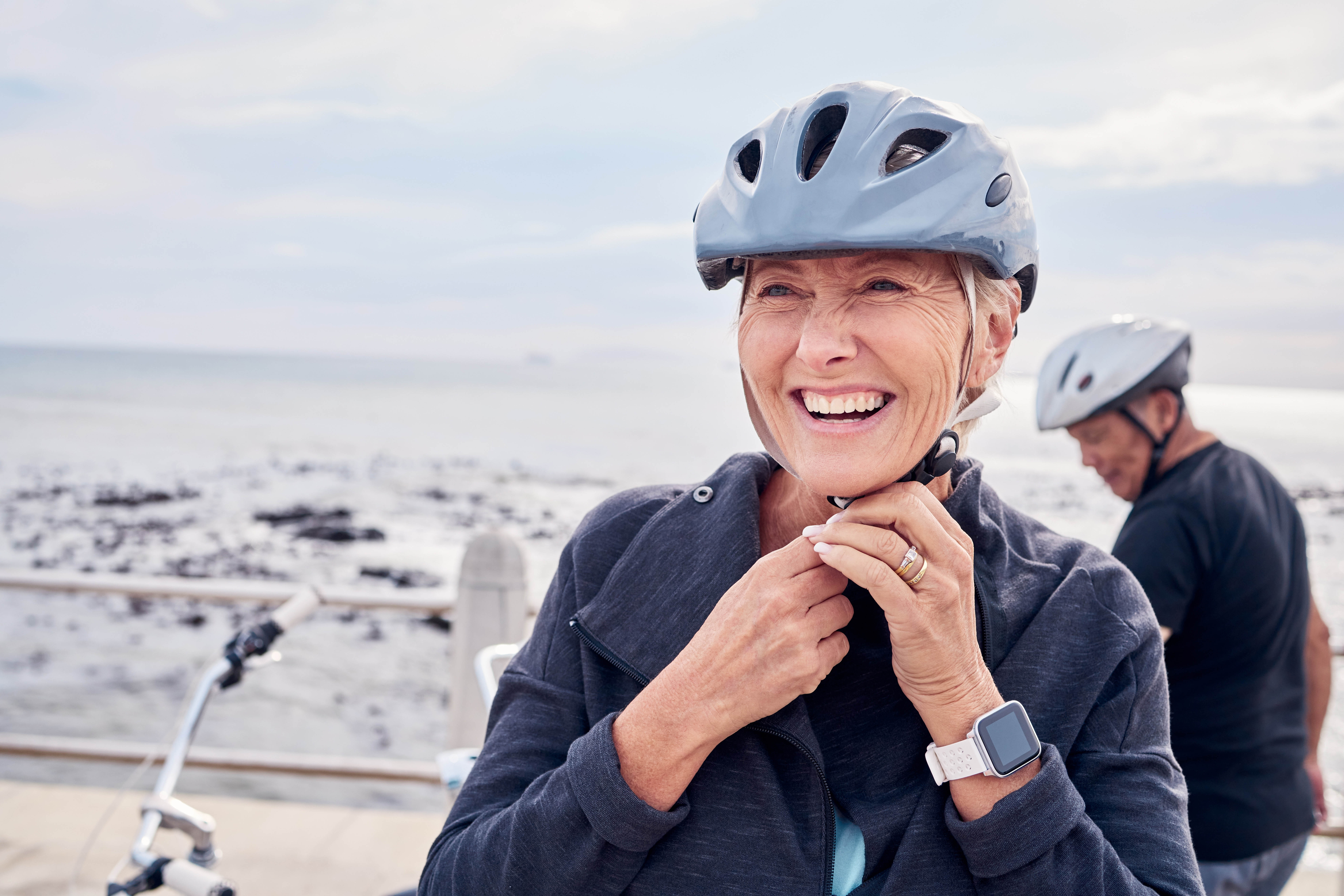 Older woman unbuckling her bike helmet Older woman unbuckling her bike helmet